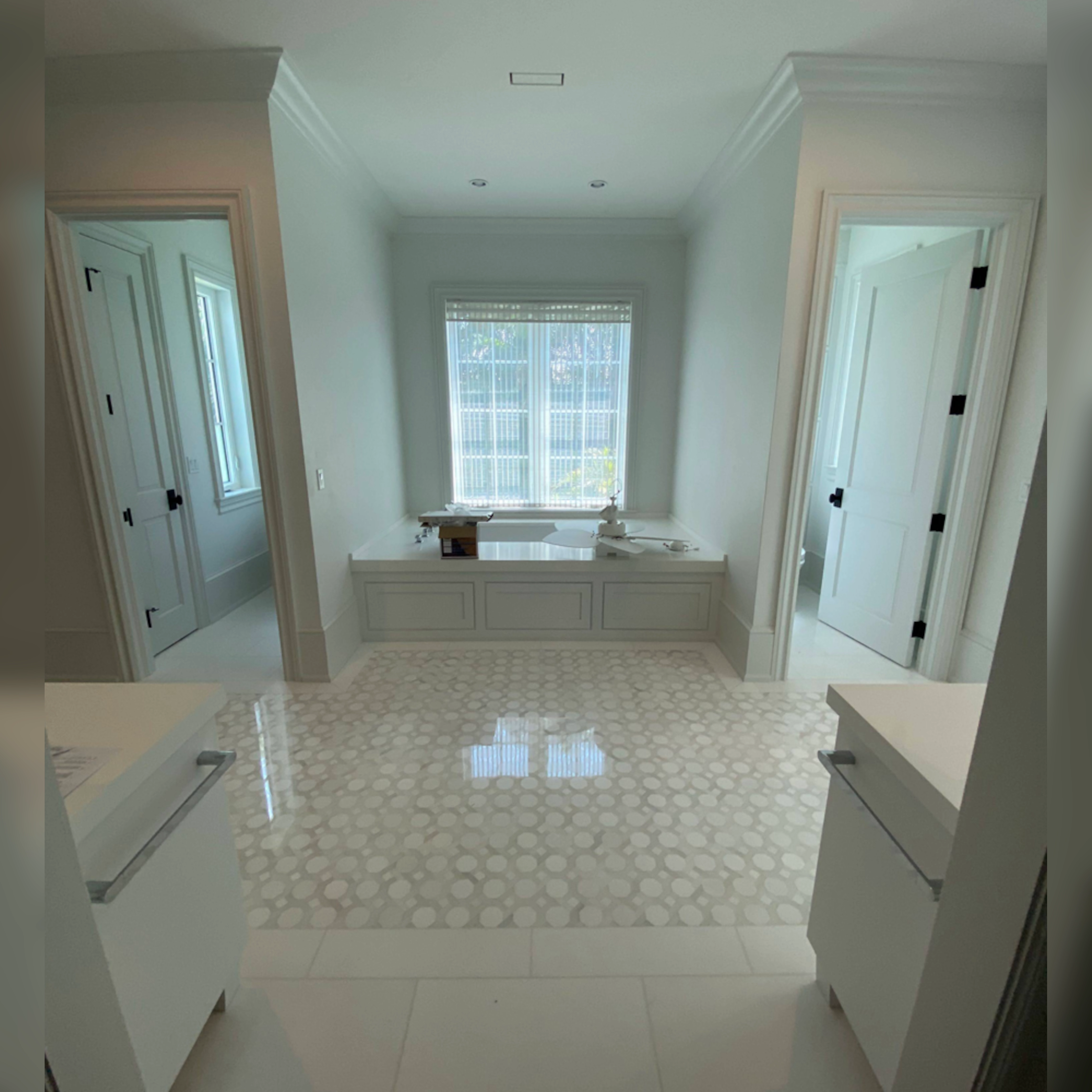 This bathroom features a stunning Thassos mosaic inset seamlessly within a field of large Thassos tiles, polished to a high-gloss, monolithic finish for a luxurious and cohesive look.