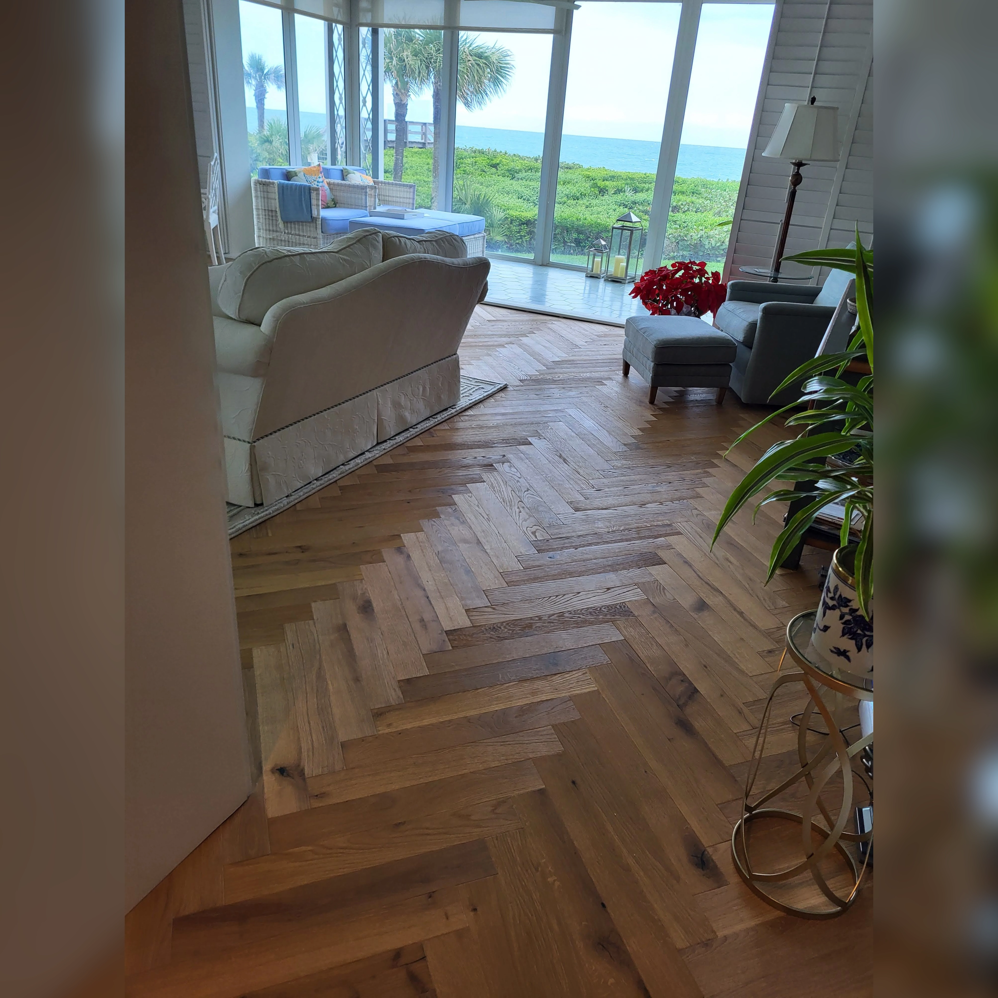 Engineered wood flooring installed in a living room featuring a diagonal herringbone pattern for a stylish and dynamic look.