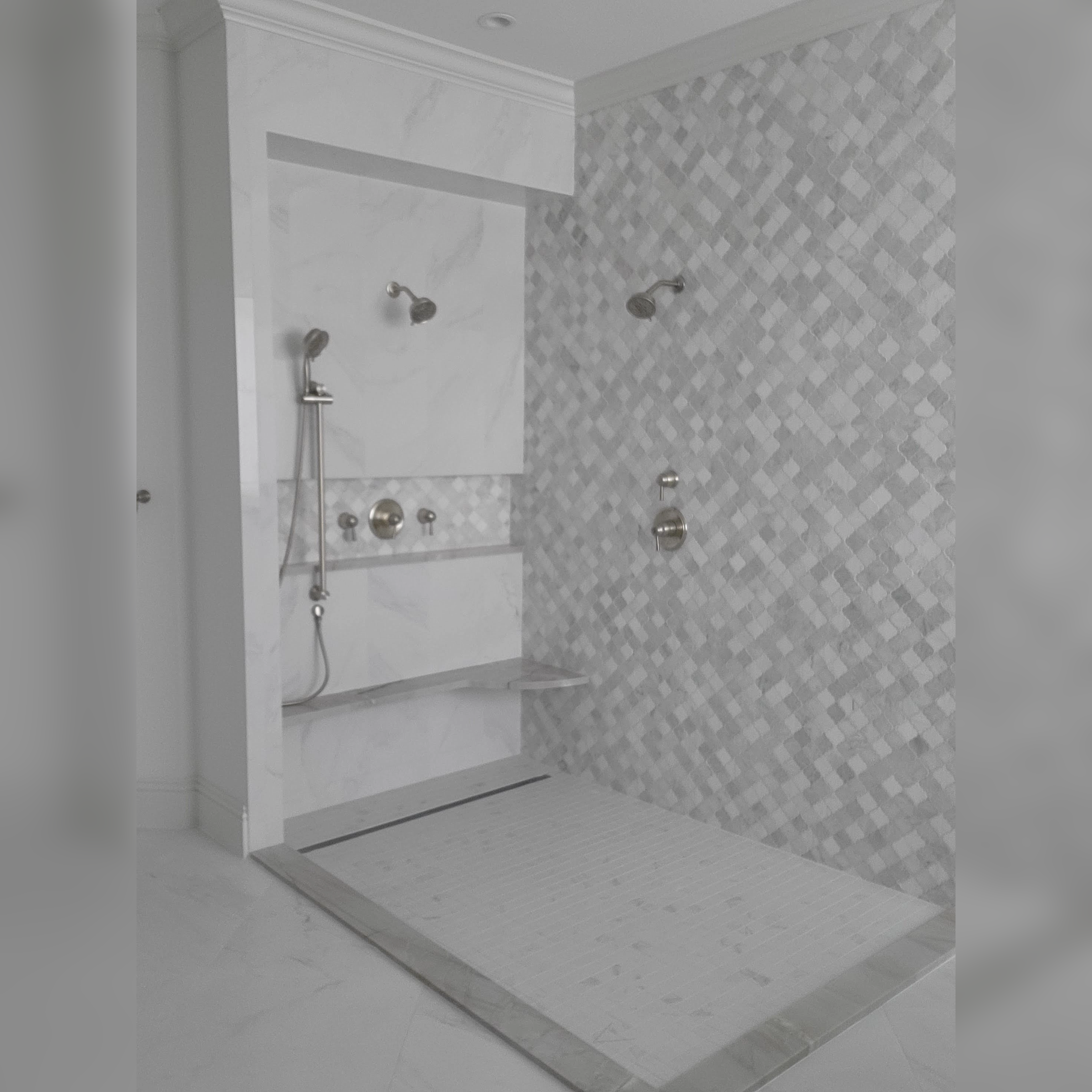 This shower features sleek porcelain walls paired with a stunning marble mosaic accent wall, a Zero Entry curb for seamless accessibility, and a linear drain for a modern, clean finish.